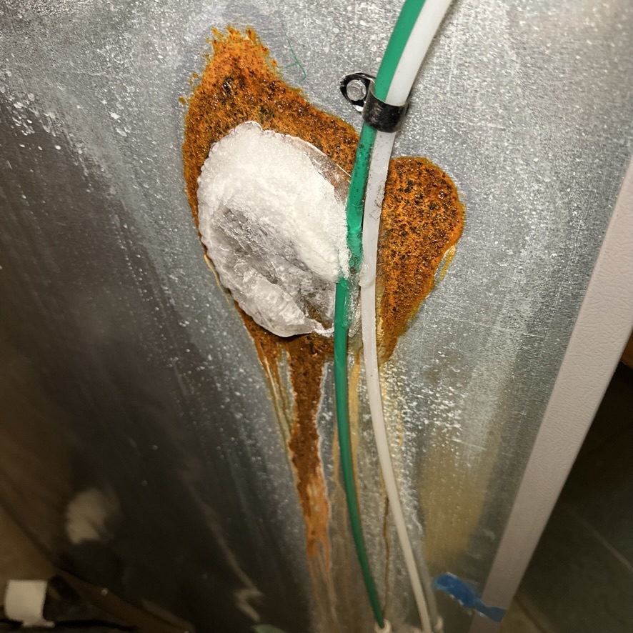 Refrigerator repair technician fixing a water line leak in Charlotte, NC.